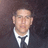 Pixelated static image of a person in formal attire with dark background, showing partial face and white shirt collar.