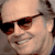 Static 50x50 pixel icon showing a close-up of a person wearing dark sunglasses with brown frames, smiling slightly against a light background.