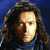 Pixelated portrait of a person with long dark hair against a blue background, wearing a dark top with light blue accents.