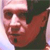 Pixelated close-up of a person's face with a light-colored headband, dark background, and visible nose and mouth.