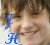 A pixelated close-up of a person's face with brown hair and light skin, featuring blue text 'JH' in the lower-left corner.