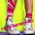 A four- shows a person's legs in white sneakers with pink laces, red striped socks, and yellow pants; the right displays 'convers4life' text over rainbow stripes
