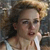 Pixelated static image of a person with light brown hair and fair skin wearing a white sleeveless top, set against a dark background with blurred elements.