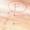 Red ink drawing of a capital letter F inside a circle on lined paper with additional red lines below.