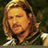 Pixelated static image of a character with long brown hair and a dark tunic against a greenish background, likely from a fantasy film or game.