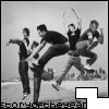 Black-and-white photo of five people in mid-jump with arms raised, set against a blurred background with text at the bottom.