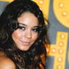 A woman with long dark curly hair and light skin smiles slightly, positioned against a yellow and gray background with circular light elements.