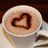 A pixelated close-up of a cup with light brown liquid and two nested heart shapes formed by darker brown patterns on the surface.