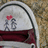 A pixelated image shows a white and maroon backpack with gray text, next to pink '<3' symbols on a brown background.