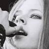Black-and-white collage of Avril Lavigne images with vertical text 'AVRIL' on black background, featuring close-ups of her face and microphone.
