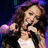 Six pixelated views of a woman with long brown hair in various poses and backgrounds, including holding a microphone and smiling.