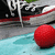 A red ball rests on a blue surface with black and white sneakers in the background, showing slight positional changes across frames.