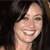 A static pixelated image shows a person with dark hair and a light skin tone smiling broadly, displaying teeth, against a dark background.