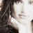 A pixelated image of a person with long dark hair, wearing a light-colored top and dark jacket, overlaid with text elements.