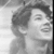 Black-and-white image of a person with curly hair smiling, shown in two side-by-side where the right is cropped differently