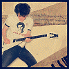 A person in a white t-shirt with 'ALLSTAR' and a graphic plays an electric guitar, surrounded by text overlays like 'ROLL' and 'ROCK AND ROLL'.