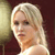 Pixelated close-up of a person with light-colored hair, wearing a light-colored sleeveless top, against a dark background with a light vertical element on the left.