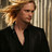 Pixelated static image of a person with light brown hair wearing dark clothing against striped background.