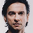 Pixelated close-up of a person with dark hair, light skin, and a neutral expression against a light background.