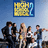 A pixelated image shows a group of people in front of a blue background with a yellow and blue framed sign above them.