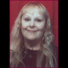 A woman with long blonde hair and glasses appears in multiple poses against a red curtain background, wearing a dark top and earphones.