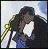 Pixelated image of two figures in close embrace, one figure with long dark hair, the other with shorter dark hair, against a light background with blurred green foliage.