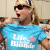 A pixelated image showing a blonde woman in sunglasses wearing a blue t-shirt with text and a pink heart, next to gray text on a pink background reading "life IS better blonde!".