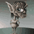 Animated pixel art character with large ears and green eyes in two sequential frames showing head movement against a gray background.