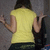A person in a yellow shirt and dark pants viewed from behind, arms raised in a shrugging gesture against a gray background.