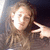 Pixelated image of a person with light brown hair holding an object near their face against a dark background.