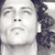 A pixelated grayscale image shows a person's face with a neutral expression, partially cropped on the right side, against a light background with dark hair visible.