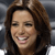 A pixelated close-up of a person with brown hair, closed eyes, and a broad smile showing teeth, set against a blurred gray background.
