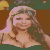 A pixelated image of a woman with long brown hair wearing a dark green top, positioned next to yellow text on a pink background.