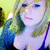 Pixelated static image of a person with light hair, blue eyes, and pink lips wearing a white top against a blurred green-yellow background.