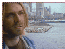 Pixelated image of a person with light brown hair wearing a blue shirt, shown in three sequential views with slight head movement against a cityscape background.