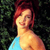Pixelated image of a person with red hair wearing a light blue top against a dark green background.