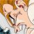 Pixelated image of two figures in close physical contact, one with light brown hair and the other with darker hair, both wearing light-colored clothing.