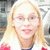 Pixelated close-up of a person with light brown hair, glasses, and pink lips against a blurred background.
