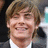 A pixelated image of a person with light brown hair and a white shirt, next to pink text on a blue background reading "Can You Get Any Cuter???".