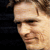 A static pixelated image shows a person's face in profile view against a dark background, with visible hair and skin tones.