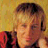 A pixelated contact sheet of two frames showing a person with light brown hair and a red patterned garment against a yellow background, next to white text reading "keith urban" on a mustard-yellow field.