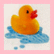 Yellow rubber duck with red beak floats on blue water splashes against light background, next to black with pink text