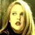 Pixelated close-up of a person with long blonde hair wearing a dark top against a blurred background.