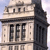 Static pixelated image of a building facade with large black letters spelling 'FEE' on a light stone surface, architectural details including columns and a cornice, and a dark vertical structure on the right.
