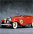Red classic car with silver accents on a gradient background, viewed from a low angle.
