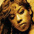 Two side-by-side pixelated frames of a person with curly brown hair against a yellow background, showing subtle facial expression changes between the left and right frame.