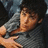 A pixelated image of a person with dark hair wearing a gray shirt, with text overlay reading 'love him<3' in white.