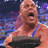Pixelated static image of a muscular person in a wrestling singlet against a dark blue background with purple and white light effects.