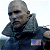Pixelated image of a bald man with dark sunglasses, wearing a dark jacket with a visible American flag patch on the sleeve.