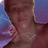 A pixelated close-up of a person's face with a blurred background showing blue and purple tones.
